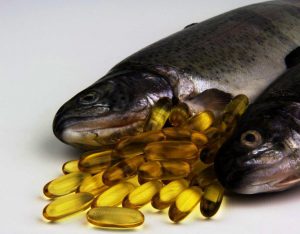 Vette vis en omega 3-capsules liggen op witte tafel 