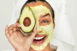 Vrouw lacht met avocado op haar gezicht