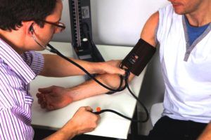 arts controleert bloeddruk bij mannelijke patiënt 