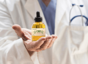 Onderzoeker in witte doktersjas huidt CBD olieflesje in de hand 