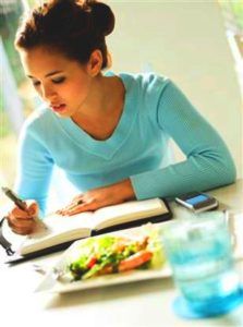 Vrouw schrijft in een eetdagboek met gezonde voeding op tafel 