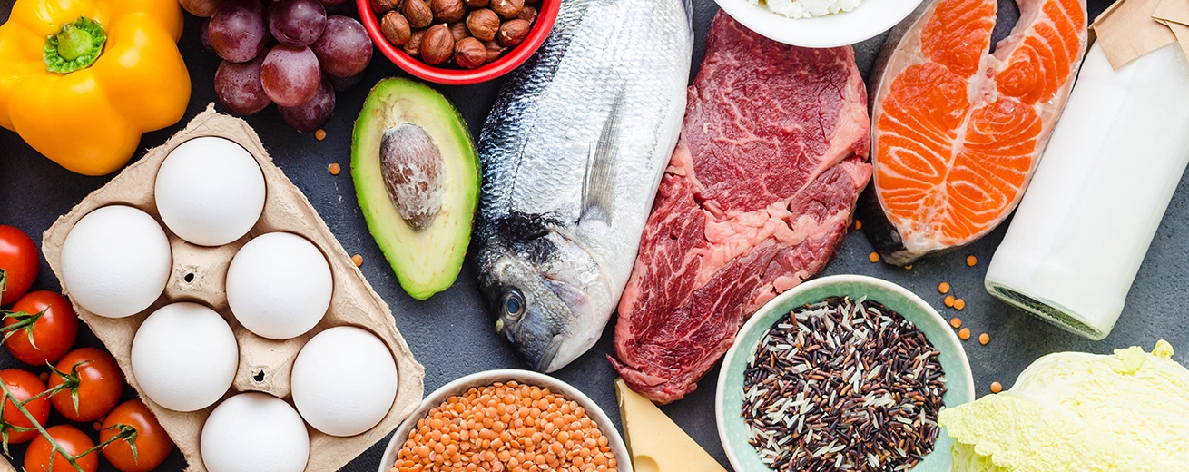 Eiwitrijke voeding zoals vlees, vis, groenten, fruit, bonen en zuivelproducten op tafel