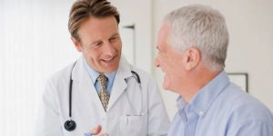 mannelijke arts lacht naar mannelijke patiënt 
