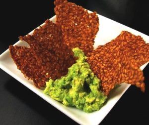 lijnzaad crackers op een wit bord met groene salade dressing