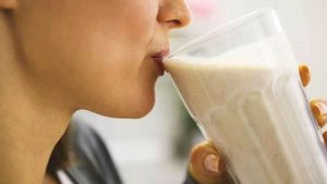 Vrouw drinkt glaasje melk uit glas