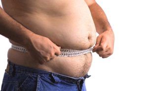 Man met overgewicht houdt meetlint om zijn middel 