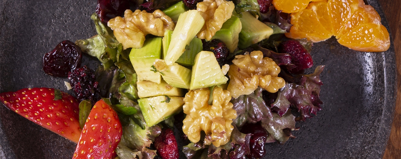 Groene salade met aardbei, braambes, bloedsinaasappelen, alligator peer, bieten, zaden en noten op een houten ondergrond