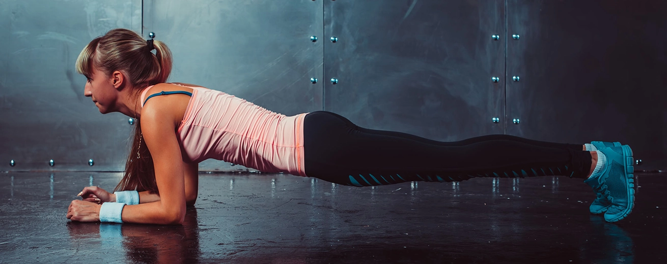 Slanke vrouw doet plank oefening in de sportschool