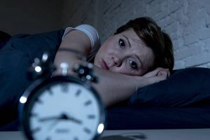 vrouw ligt in bed en heeft last van slapeloosheid