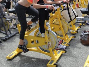 sporters doen aan spinning op gele fietstrainer