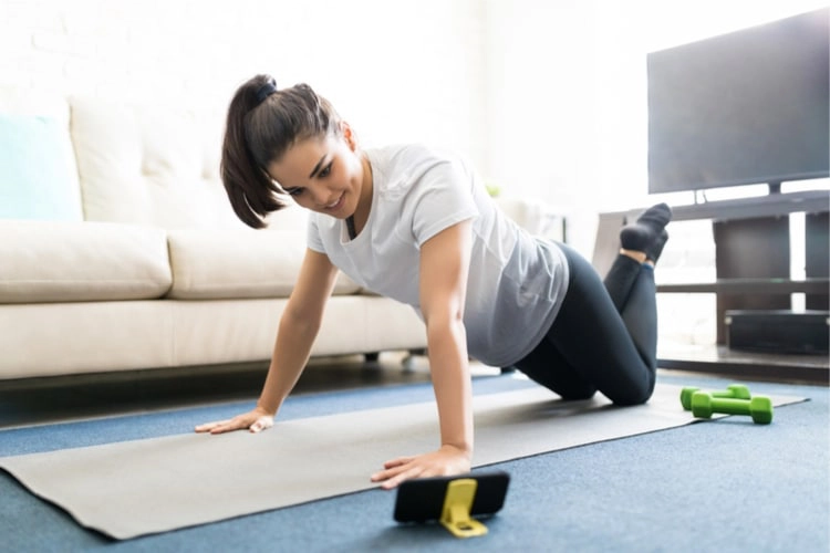 Vrouw doet tabata workout op yoga matje in huiskamer