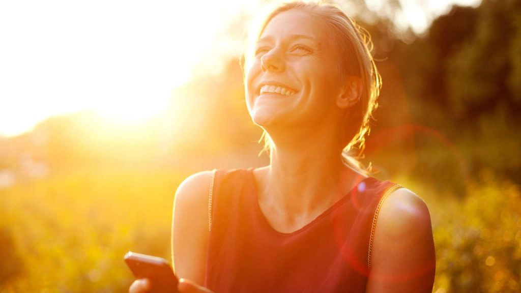vrouw lacht buiten tijdens zonnige dag