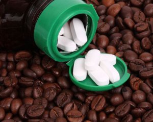 witte pillen in een groen potje met koffiebonen op de achtergrond