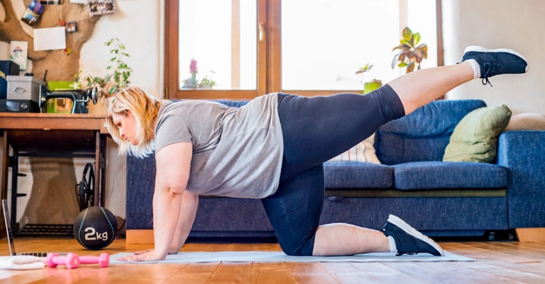 Vrouw met overgewicht doet een thuis workout op een fitnessmatje