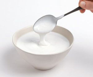 yoghurt drupt uit lepel boven kommetje